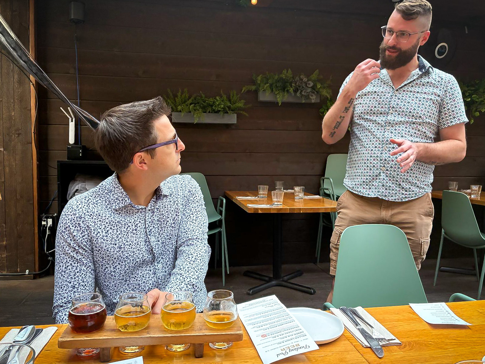 Photo of a man enjoying a flight of beer tasting while the beer master instructs